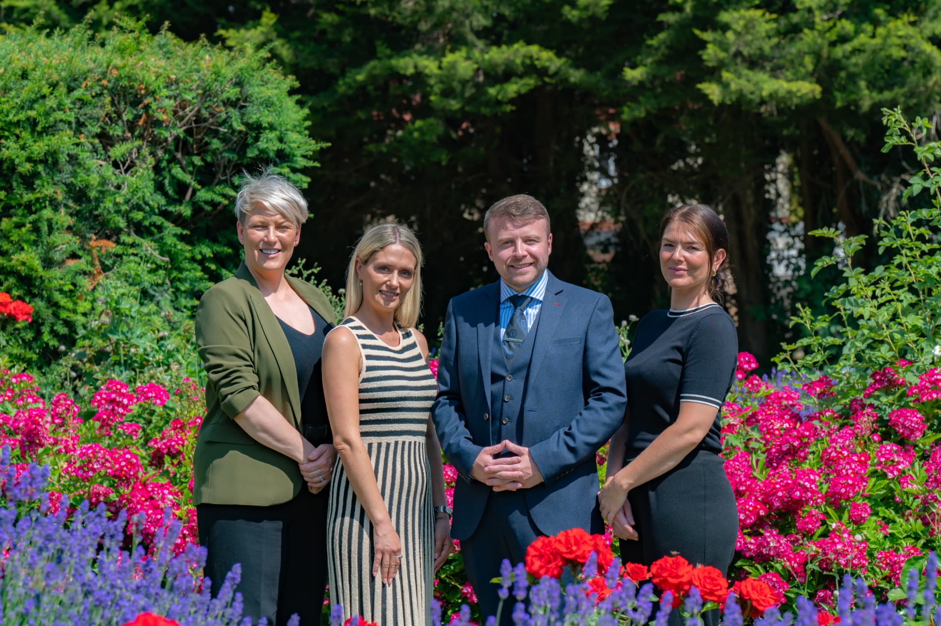 The Valentines Family Funeral Directors team standing together in a summer garden